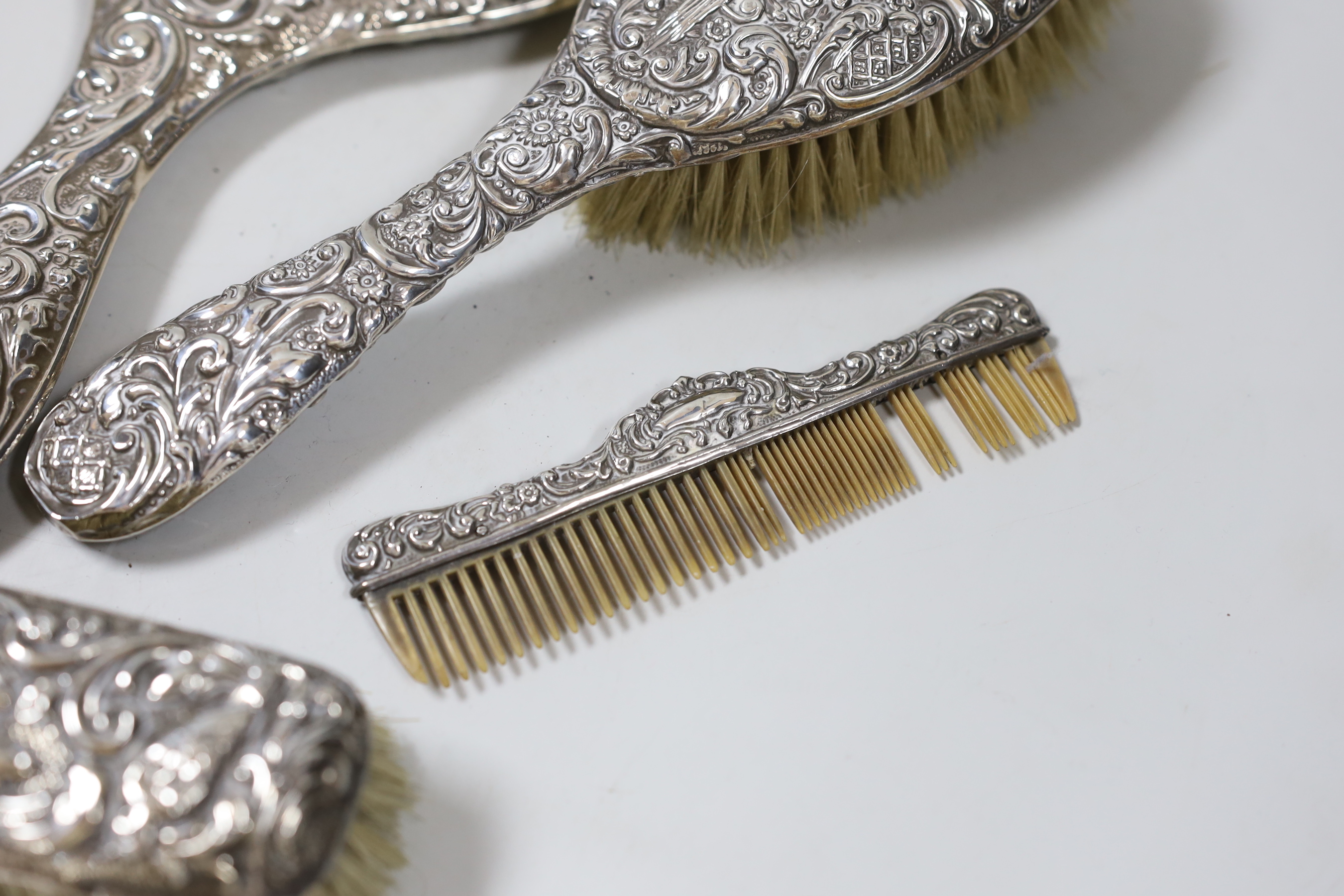 A late Victorian repousse silver mounted six piece mirror and brush set, Chester, 1900.